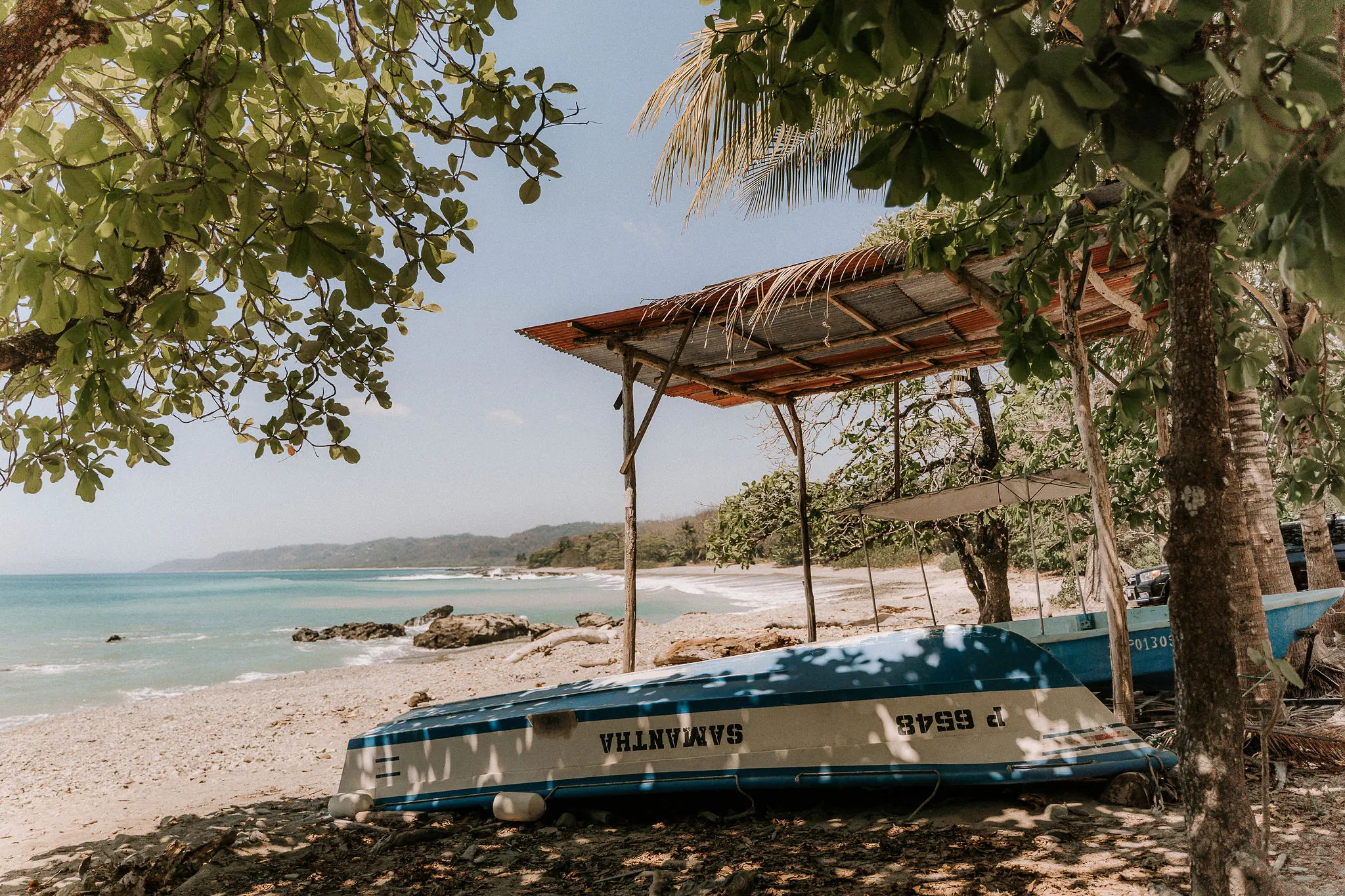 Fishing boat resting under a palapa on the beach